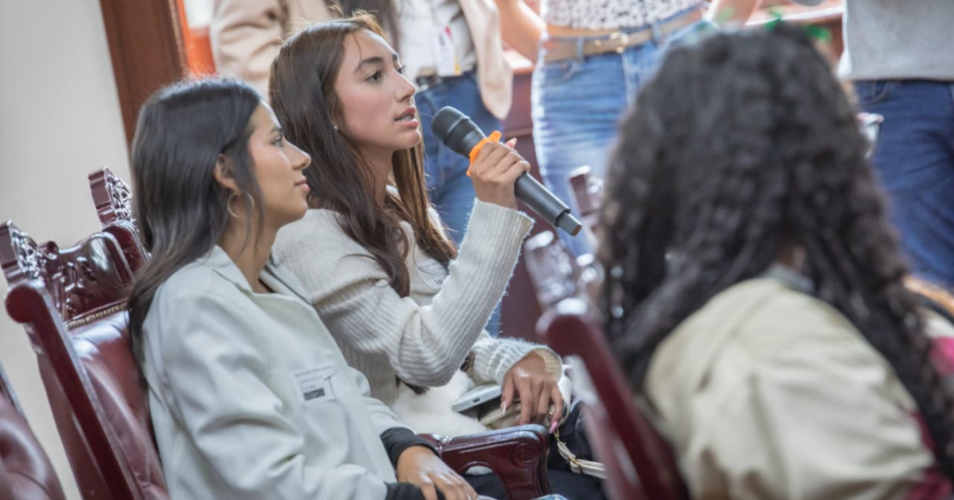 Foto de una mujer hablando por micrófono 