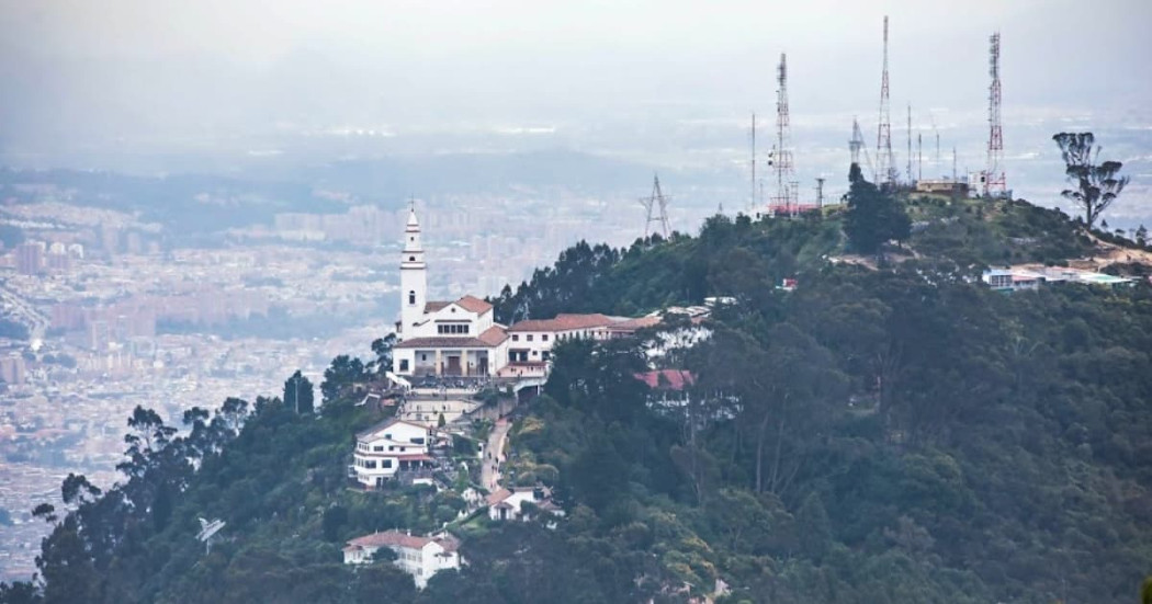 Vista del Santuario de Monserrate en cerro boscoso con ciudad de Bogotá al fondo