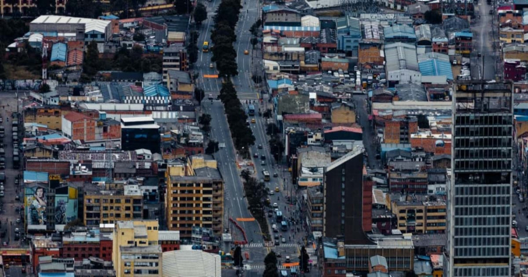 Vista aérea de avenida central de Bogotá con edificaciones densas y tráfico moderado