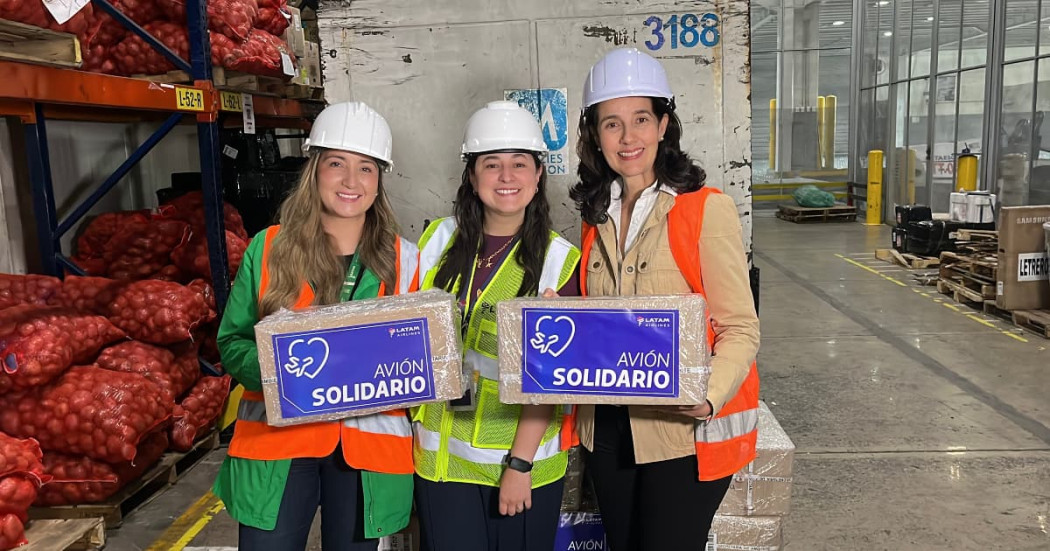 Secretaria de Ambiente, Adriana Soto, sostiene caja rotulada “AVIÓN SOLIDARIO” en bodega durante operación humanitaria