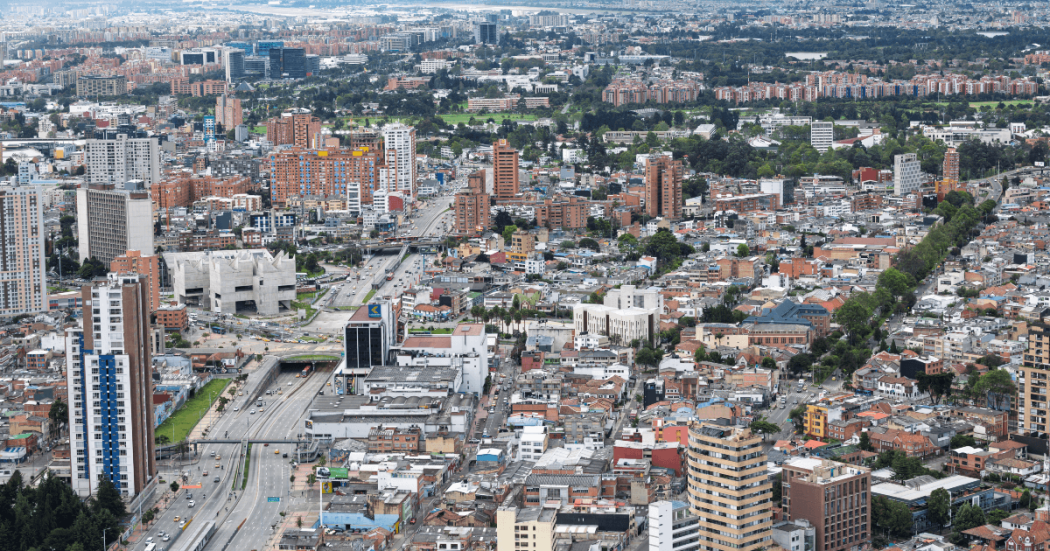 Vista panorámica de Bogotá con edificaciones residenciales y comerciales, avenidas principales y amplia expansión urbana observada desde gran altura.