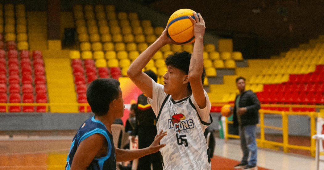 Jóvenes disputan partido de baloncesto en escenario deportivo cubierto de Bogotá.