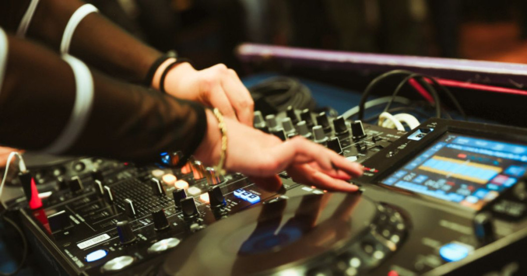 Imagen de consola de música eléctronica con manos de mujer tocando discos
