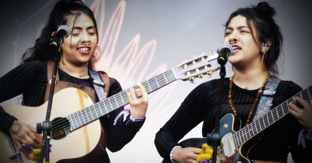 Imagen de Briela Ojeda e Isabel Ramírez “La Muchacha” tocando guitarras en concierto.