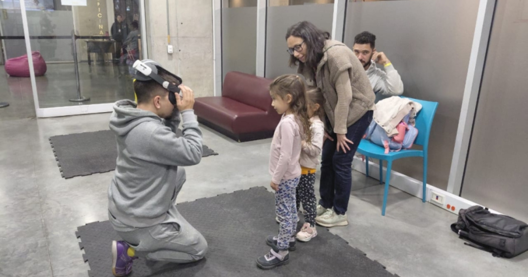 Imagen de un niño arrodillado jugando con lentes 3D mientras dos niñas y una mujer lo observan
