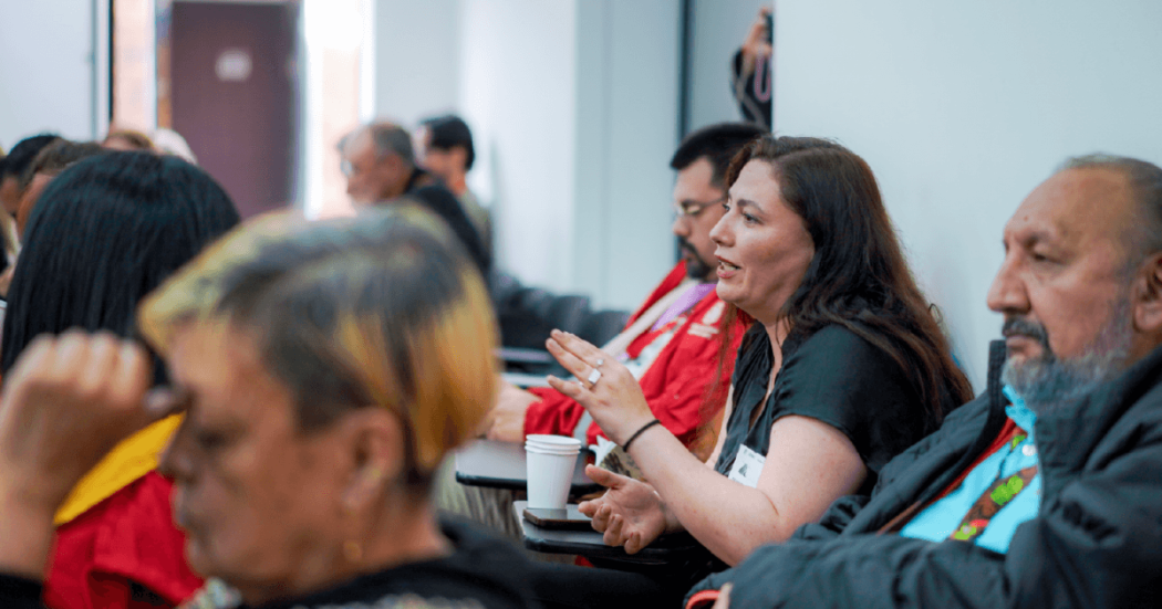 Mujer en el público de un evento o charla, hablando.