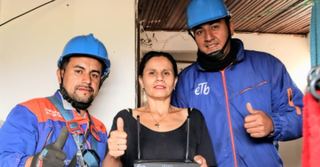 Imagen de dos operarios de etb junto a una señora sonriendo