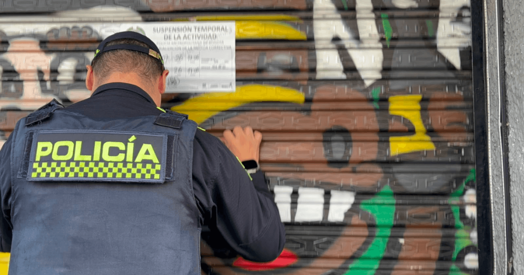 Policía pegando un aviso de suspensión temporal en un establecimiento del Siete de Agosto