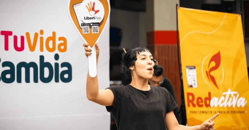 Mujer con una pancarta dando información sobre la trata de mujeres, desde la Red Activa.