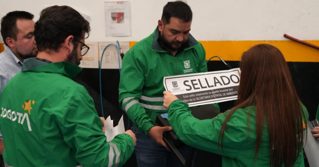 Personal de entidades distritales realiza procedimiento de control ambiental en establecimiento. Una funcionaria sostiene aviso con texto que dice “SELLADO”, mientras otros funcionarios participan en la diligencia de inspección y cierre.