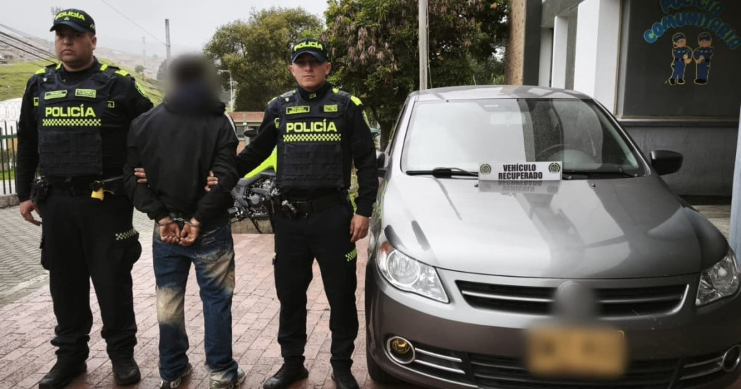 Dos policías con hombre capturado y vehículo recuperado.