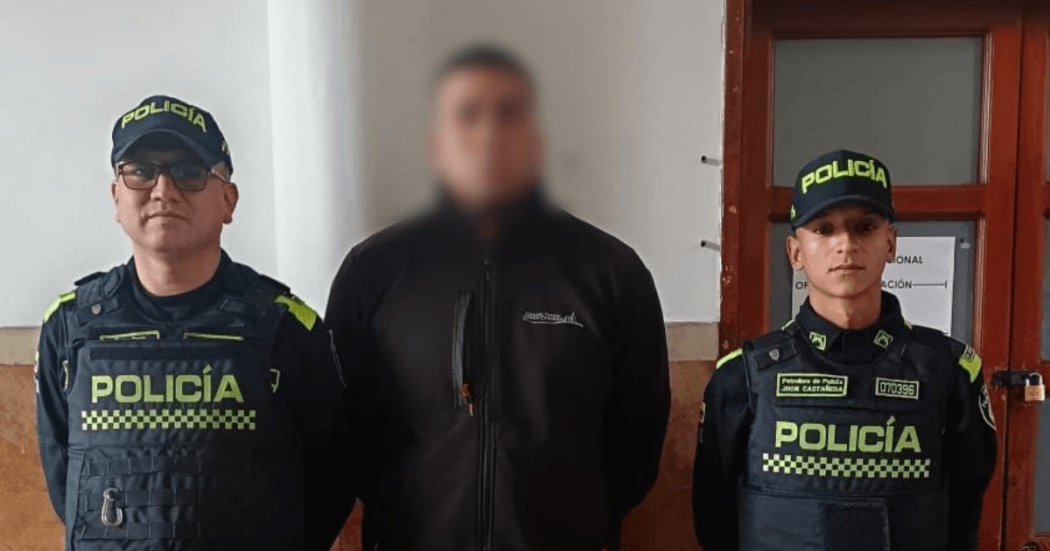 Hombre capturado por hacer 'cambiazos' de tarjetas, en medio de dos uniformados.