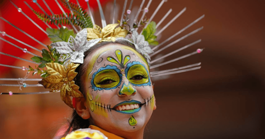 Primer plano de artista con maquillaje artístico inspirado en la cultura mexicana con tocado floral durante una presentación cultural del lanzamiento del Festival de Verano 2026 en Bogotá.