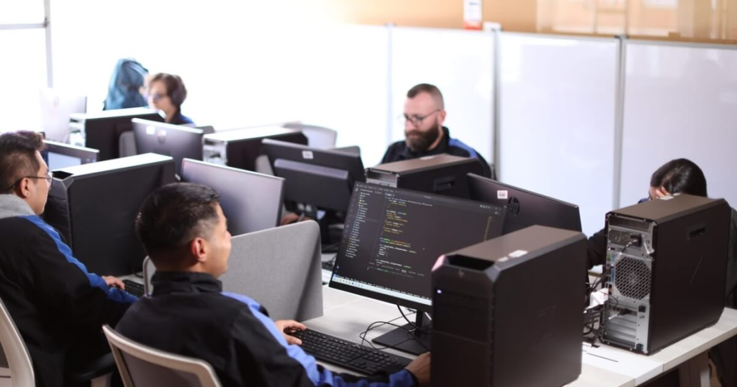 Foto que muestra personas trabajando frente a computadores 