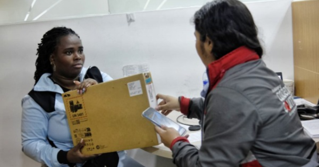 Imagen de una funcionaria entregando un computador a una mujer