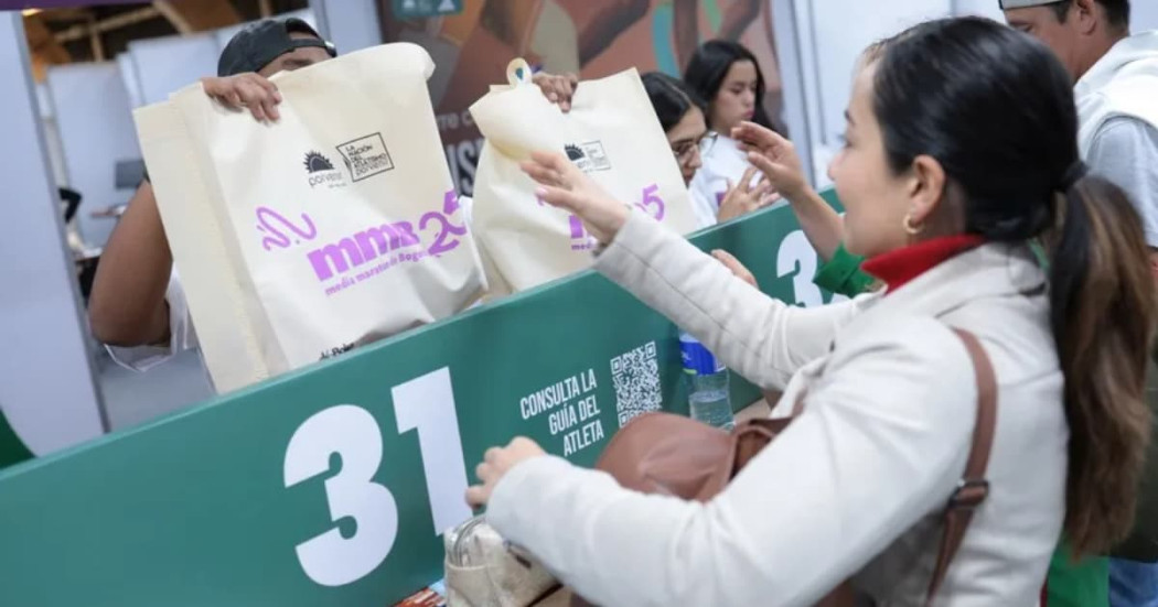 Una mujer recibiendo el kit de la carrera de la media maratón de Bogotá