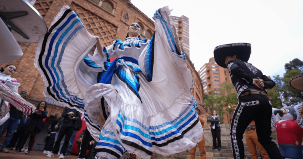 Bailarines con trajes folclóricos y mariachis realizan una presentación cultural al aire libre frente a una edificación de ladrillo durante lanzamiento del Festival de Verano 2026 en Bogotá.