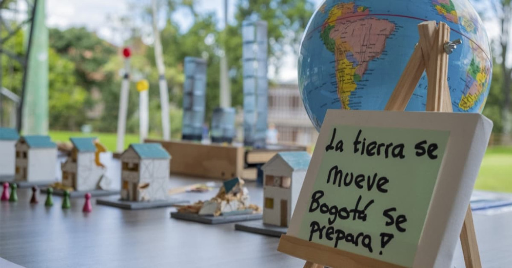 Mesa educativa sobre sismos con maquetas, globo terráqueo y cartel con texto “La tierra se mueve Bogotá se prepara!”.