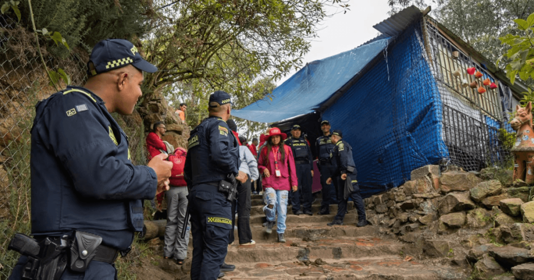 Policías y autoridades en sendero de Monserrate realizan operativo de sellamiento de estructura cubierta con lona azul y vegetación alrededor.