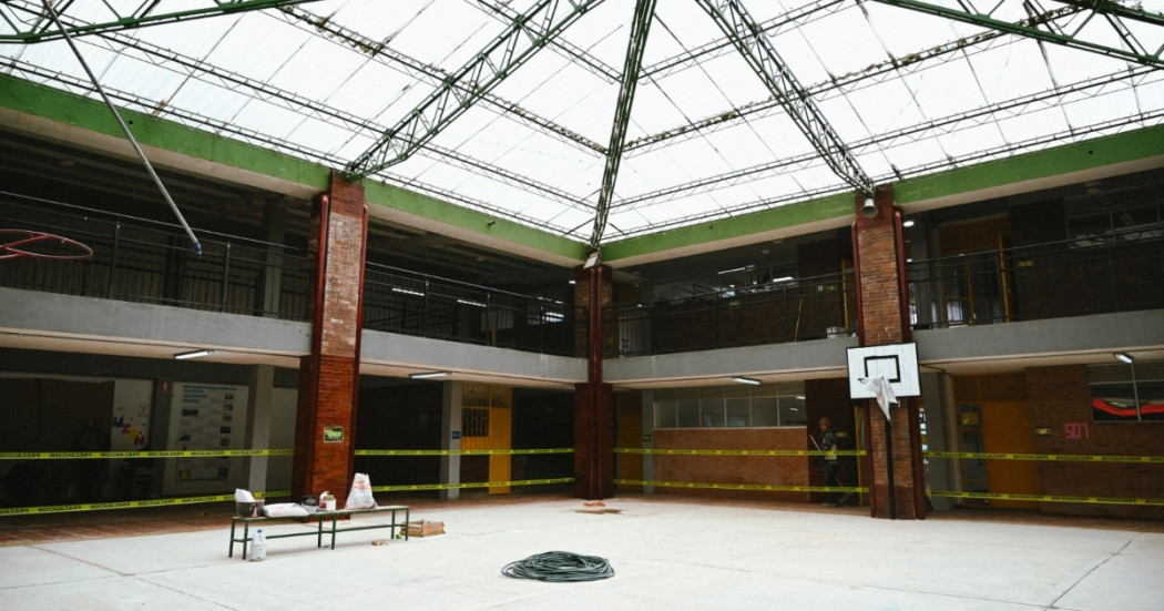 Foto que muestra el patio de un colegio con cancha de baloncesto y techo cubierto