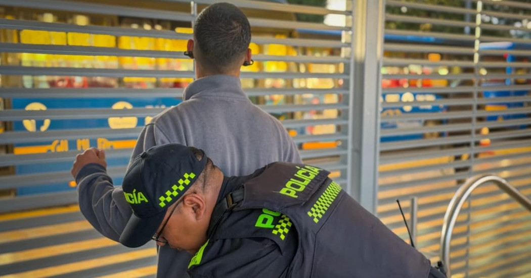 Un policía requisando a un ciudadano en una estación de TransMilenio.