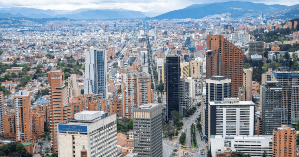 Vista panorámica de Bogotá con torres residenciales y empresariales, corredores viales, alta concentración de edificaciones y cerros orientales al fondo.