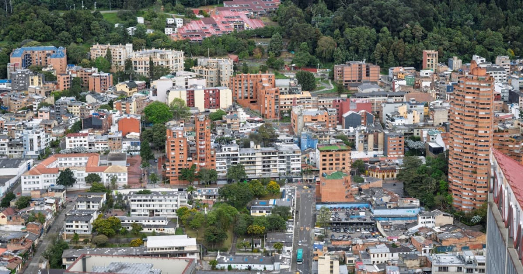 Vista aérea de Bogotá con edificaciones residenciales y cadena montañosa verde al fondo