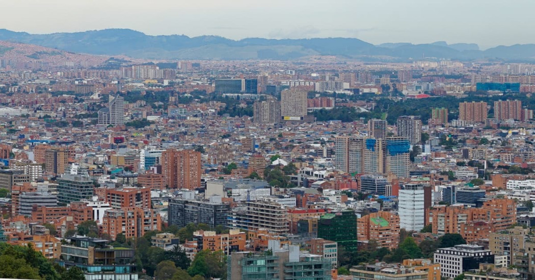 Vista panorámica de Bogotá con edificaciones residenciales y comerciales, cerros orientales al fondo y paisaje urbano.