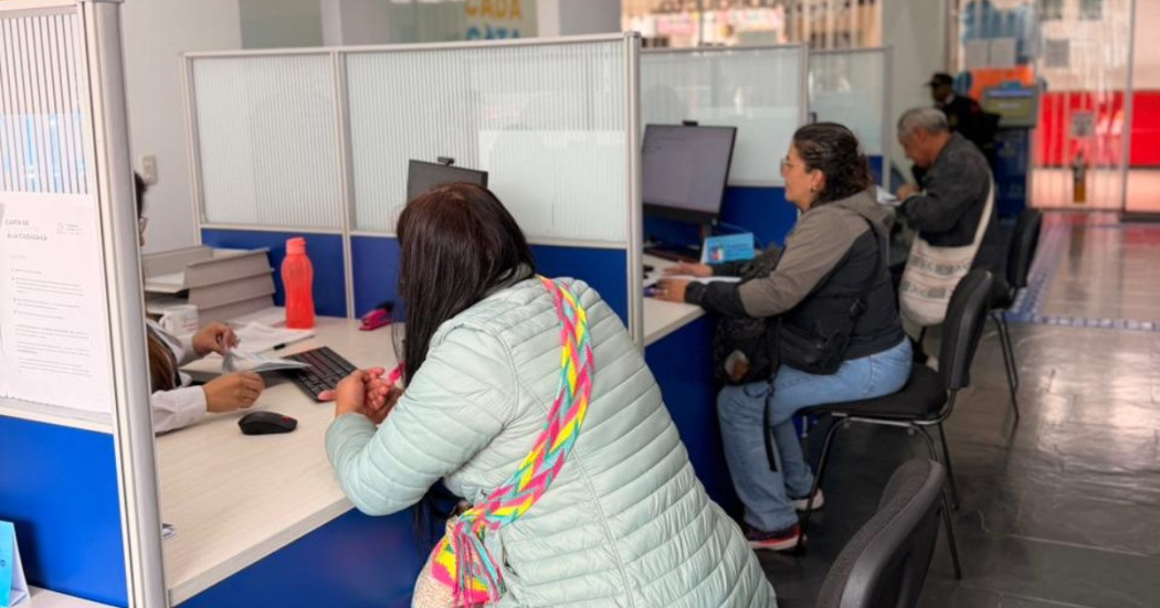Foto que muestra tres personas sentadas frente a modulos de atención 