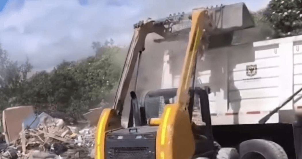Foto que muestra un tractor recolectando basuras en una volqueta 