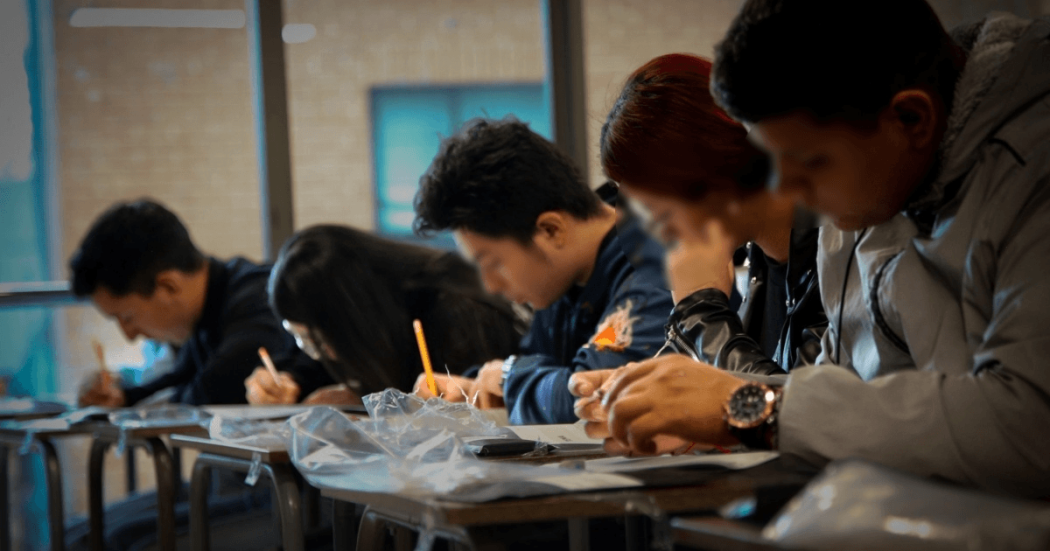 Foto que muestra personas escribiendo en un papel 