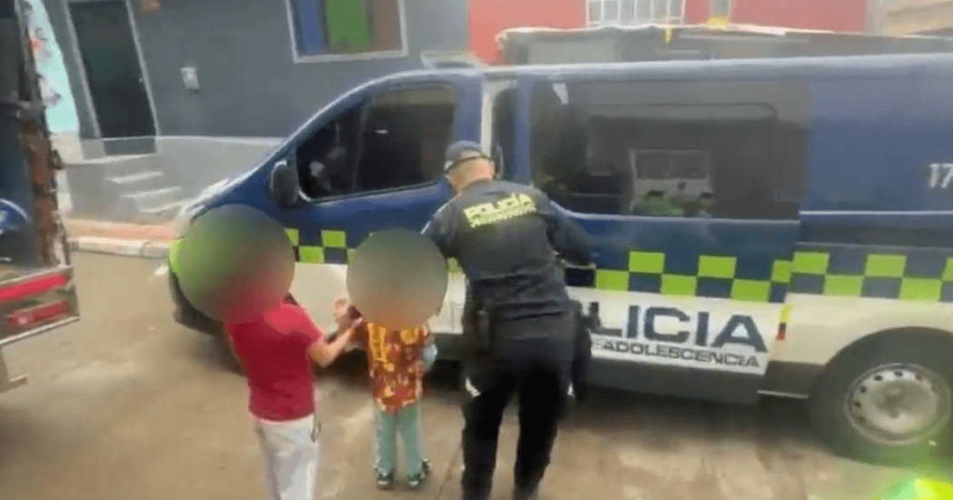 Dos niños rescatados, de la mano con un policía.
