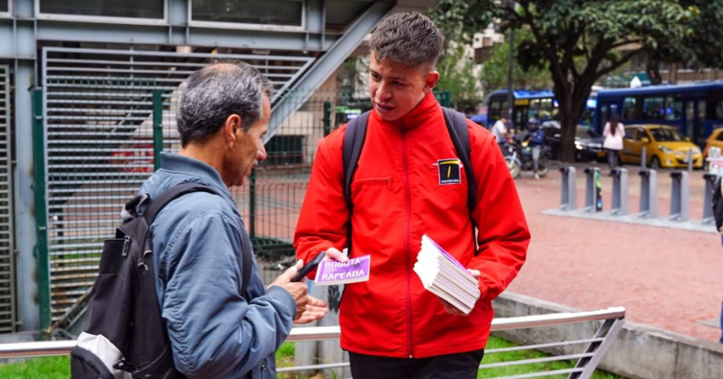 Foto de u funciionario entregando un libro a un ciudadano 