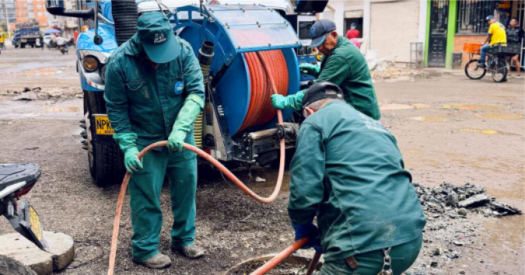 Imagen de tres técnicos de la empresa de Acueducto realizando mantenimiento en un tubo de alcantarillado, de fondo se ve un carro tanque.