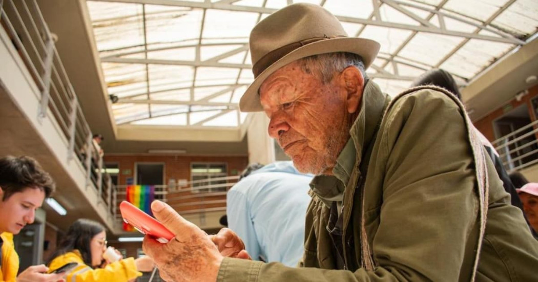 Un adulto mayor en Bogotá, revisando su celular.