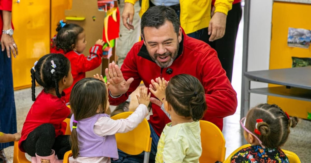 El alcalde Carlos Fernando Galán sonriendo con unos niños y niñas de un jardín infantil.