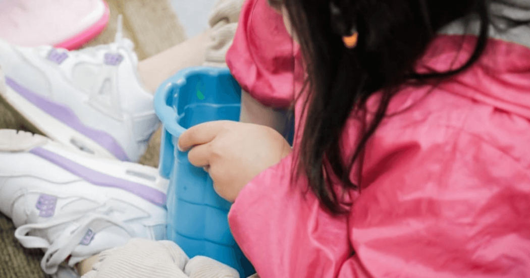 Niña jugando en el piso con un balde.