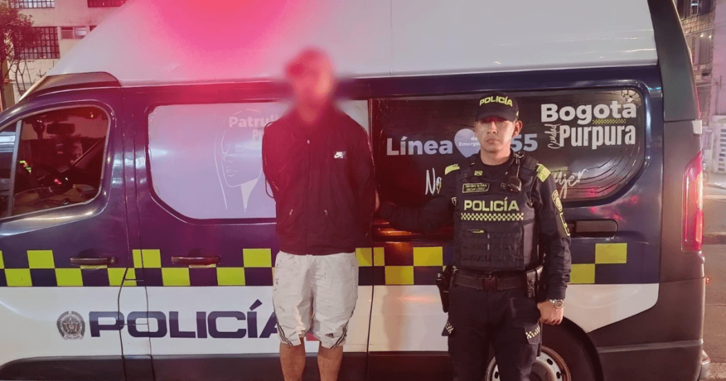 Hombre capturado junto a un policía y una patrulla.