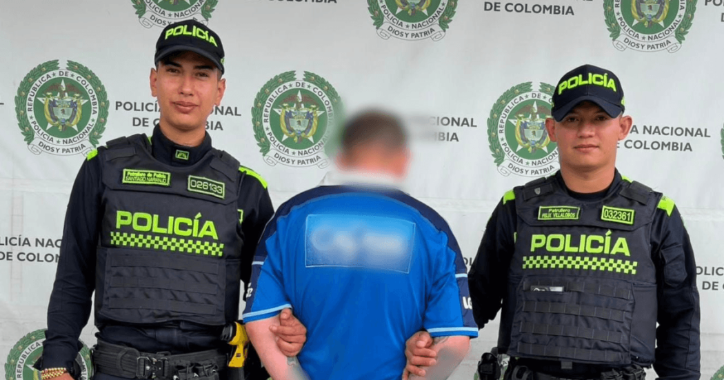 Hombre capturado, de espaldas, en medio de dos policías.