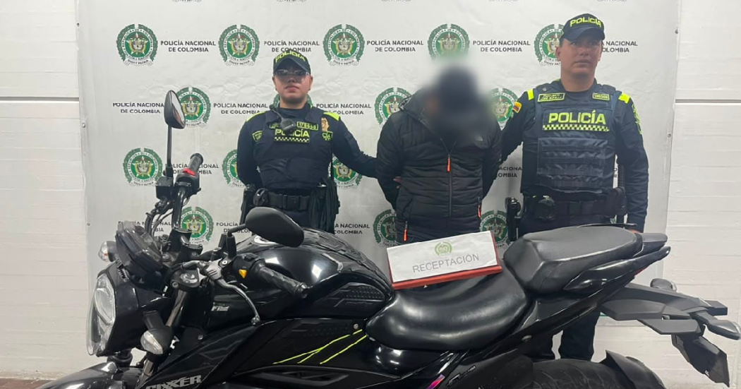 Foto de uniformados de la Policía con el hombre capturado y la motocicleta incautada.