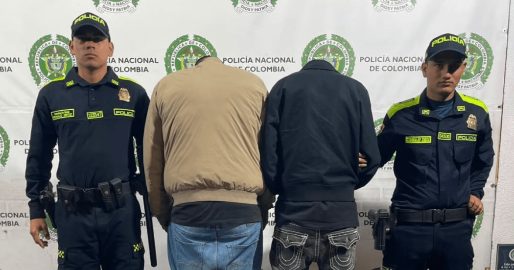 Dos 'rompevidrios' capturados, de espaldas en medio de dos Policías.