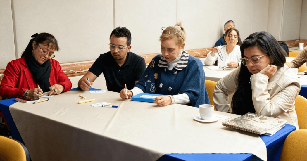 Foto que muestra personas sentadas escribiendo en un escritorio 