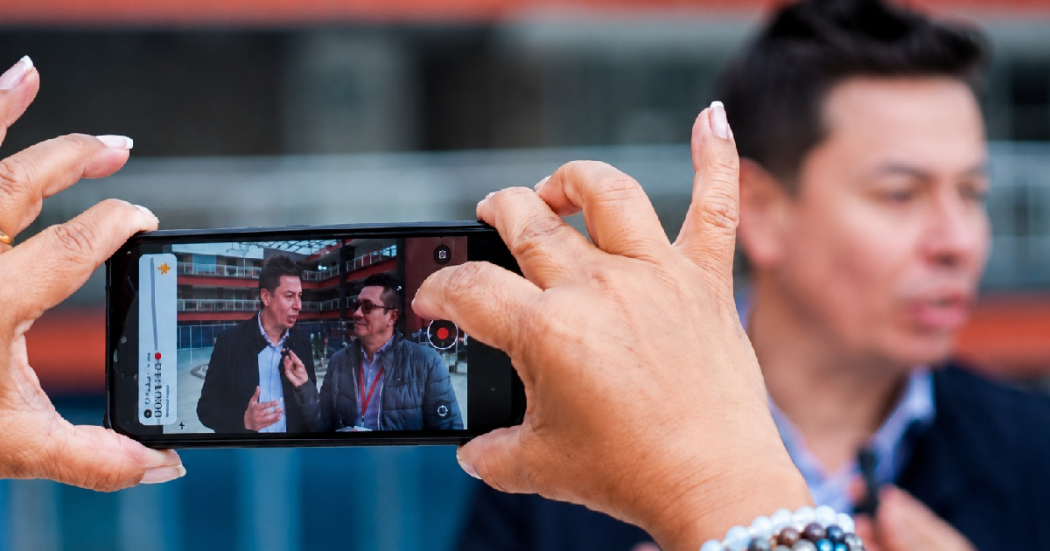 Persona sosteniendo celular en las manos en un medio comunitario de Bogotá.