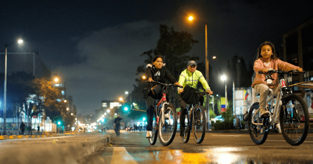 Tres personas recorren una vía durante la Ciclovía Nocturna en Bogotá.