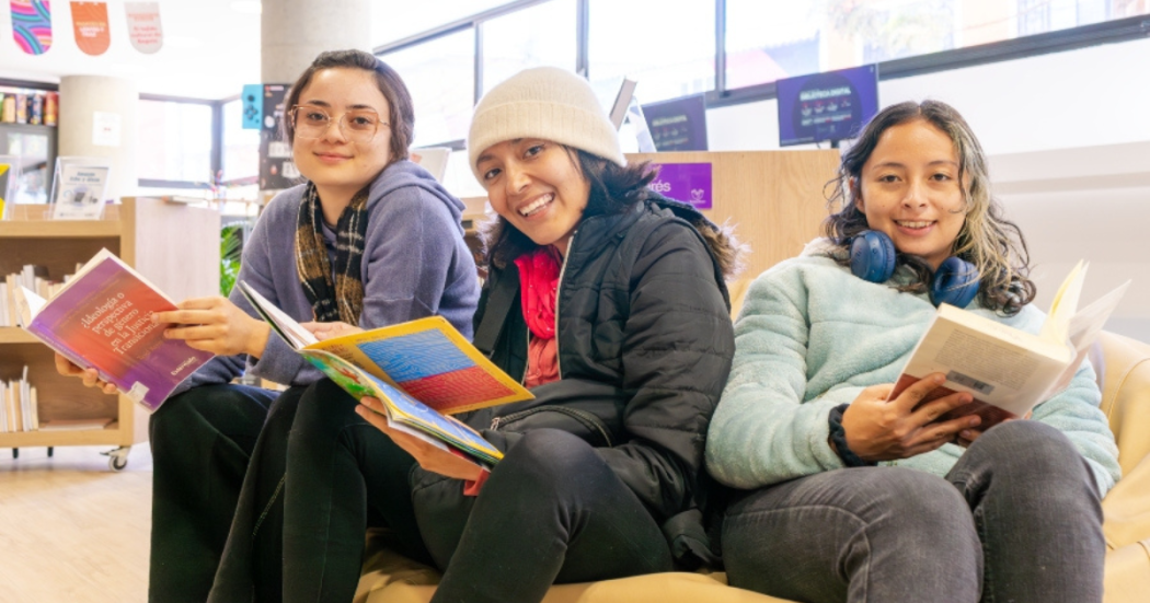 Imagen de tres mujeres sentadas con libros en las Bibliotecas Públicas de Bogotá.