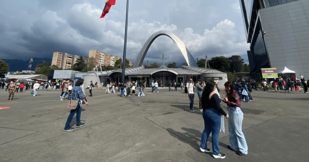 Vista exterior de Corferias en Bogotá con personas transitando por la plaza principal, el arco de acceso al centro de eventos.