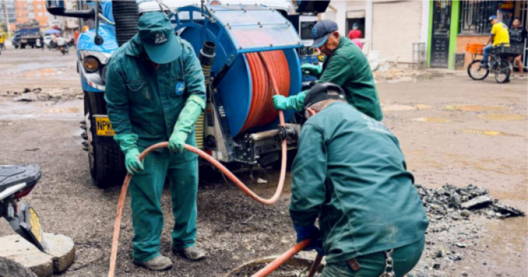 Imagen de tres técnicos de la empresa de Acueducto realizando mantenimiento en un tubo de alcantarillado, de fondo se ve un carro tanque.