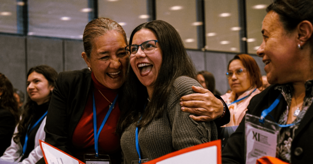 Mujeres sonriendo y abrazándose en un encuentro en Bogotá.