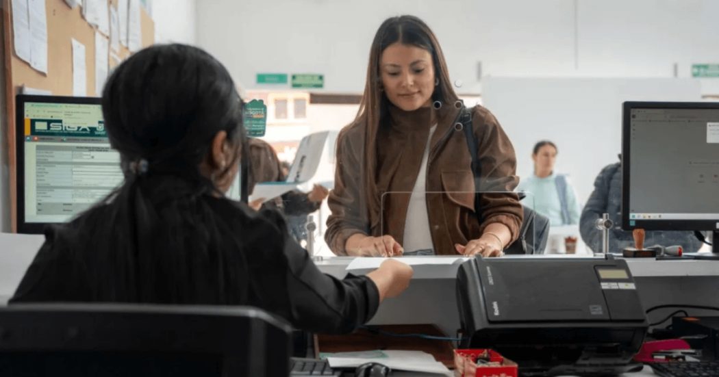Foto que muesta dos mujeren hablando, computadores y una impresora