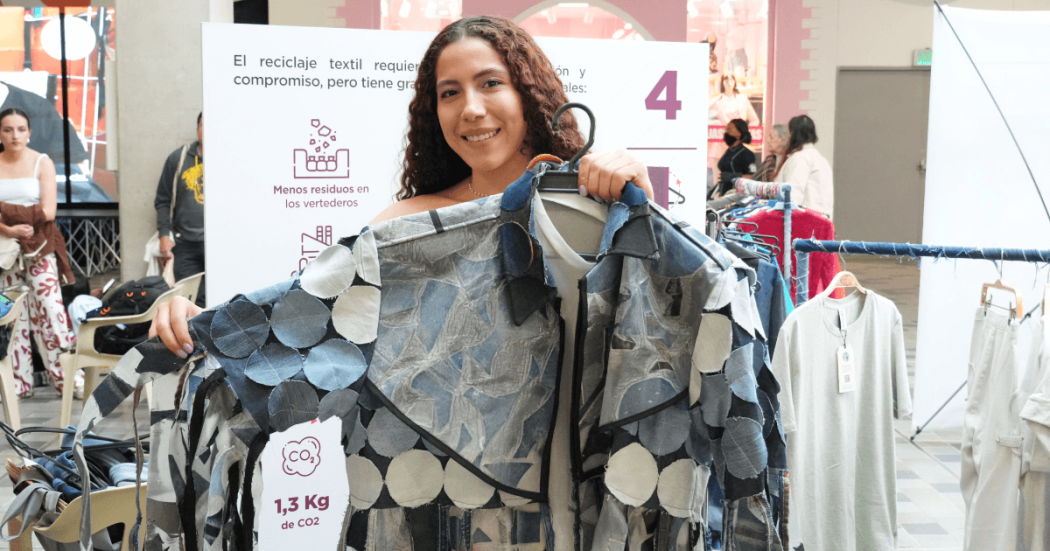 Persona sostiene una prenda elaborada con retazos textiles en una muestra sobre reciclaje de ropa.